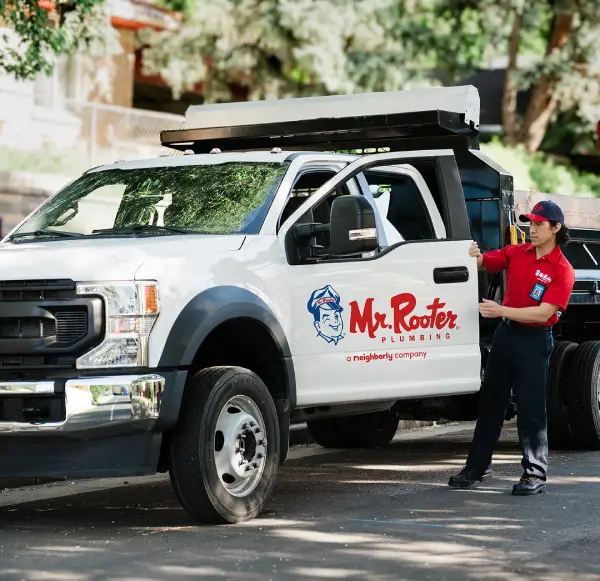 A Mr. Rooter Plumbing professional exiting a branded truck.