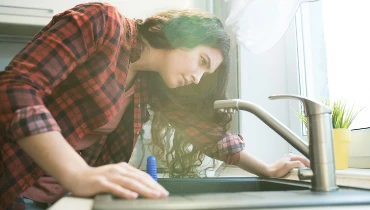 A girl looking into a clogged drain.