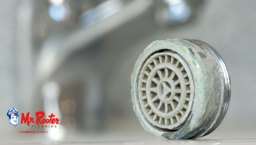 A shower head with limescale buildup on a bathroom countertop.