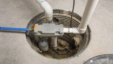 Sump pump in a hole in cement surrounded by pipes