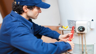 Plumber using a wrench to repair a water heater.