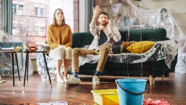 Water Drips into Buckets in Living Room. Angry Couple in Background Calling Insurance Company | Mr. Rooter Plumbing of South Jersey