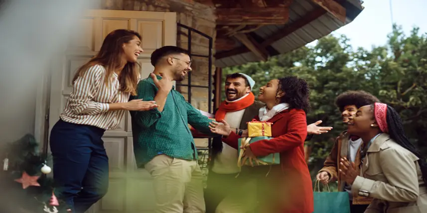 Young happy couple greeting holiday guests outside