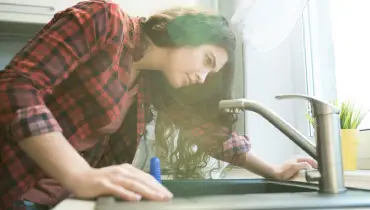 woman looking down a drain.