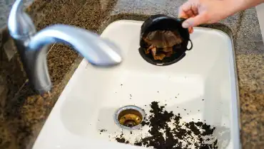 Coffee grounds being dumped into a sink.