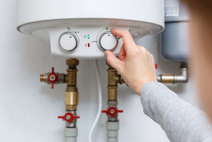 A woman’s hand adjusts the dial on an electric water heater. | Mr. Rooter Plumbing of The Oakland-Berkeley Area