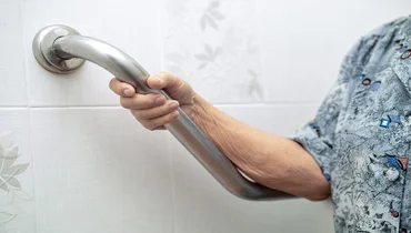 Asian senior using a grab bar in the bathroom 