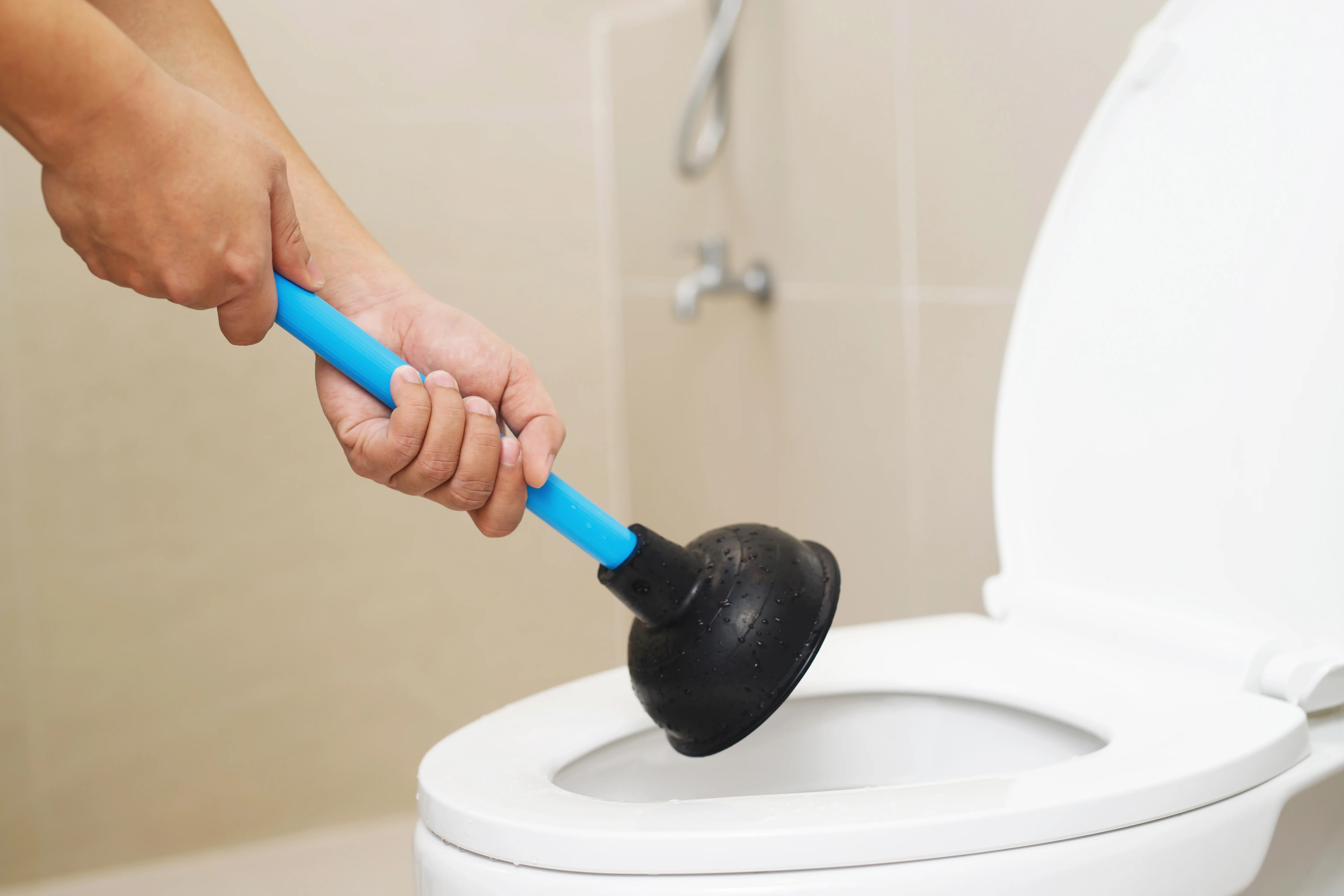 Serviceman repairing toilet with hand plunger. Clogged toilet.