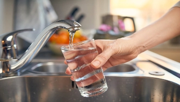 Someone getting fresh tap water from a kitchen sink