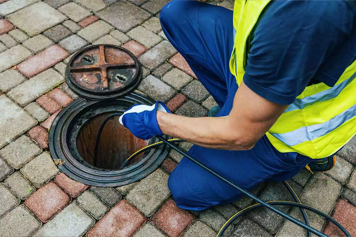 Photograph of a service professional clearing a clogged sewer line.