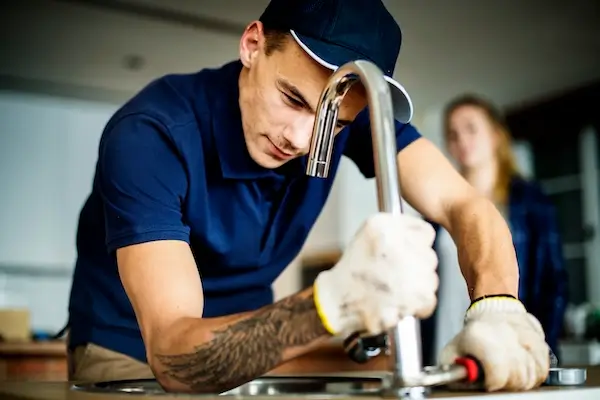 A plumber fixing a kitchen faucet during a kitchen remodeling project