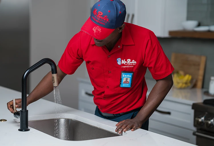 Mr. Rooter plumber working on a kitchen sink during a sink repair appointment 