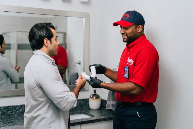 Mr. Rooter plumber explains leaking pipe repair while showing the homeowner a drain pipe.